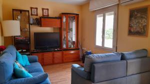 Sala de estar con 2 sofás azules y TV en Apartamento con piscina y bonita terraza, en Segur de Calafell