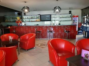 a restaurant with red chairs and a bar at Restaurant and Pension Stenly in Spišský Štvrtok