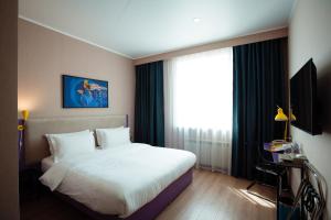 a bedroom with a white bed and a large window at City Hotel Shymkent in Shymkent