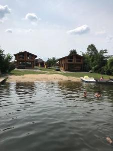 a couple of people in the water in front of houses at Берег Світязя in Svityazʼ