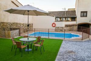 una mesa y sillas con una sombrilla y una piscina en 'El Charcón' Casa con piscina compartida, en Torrico