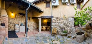 un edificio de piedra con un patio con mesa y sillas en 'El Charcón' Casa con piscina compartida, en Torrico