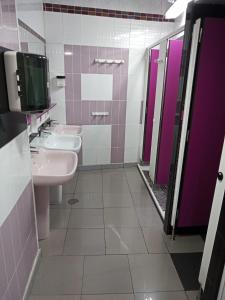 a bathroom with three sinks and purple stalls at A Fonte De Compostela in Santiago de Compostela