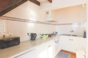 a kitchen with white cabinets and a black microwave at Beachfront Casa da Praia in Porto Formoso