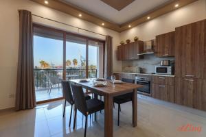 a kitchen with a wooden table and chairs and a large window at Luxurious Duplex Seafront Apt w Amazing Sea Views in Birżebbuġa