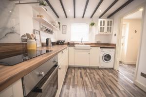 Poachers Cottage في ليبرن: مطبخ مع خزائن بيضاء وغسالة ومجفف