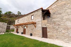 - un bâtiment en pierre avec deux portes et une pelouse dans l'établissement Casas da Fonte - Turismo Rural, à Vila Verde