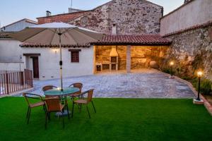 a patio with a table and chairs and an umbrella at A - Apartamento elegante con piscina compartida in Torrico