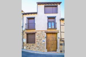 a stone house with a wooden door on a street at A - Apartamento elegante con piscina compartida in Torrico