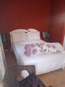 a hotel room with two beds and a chair at Mongilo Guesthouse in Windhoek