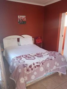 a bedroom with a white bed with flowers on it at Mongilo Guesthouse in Windhoek