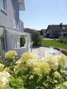 a garden with white flowers in front of a white door at Barrierefreies Appartement auf der Alb in Trochtelfingen