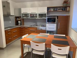eine Küche mit einem Holztisch und weißen Stühlen in der Unterkunft Apartmány Čertovka in Harrachov