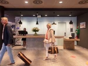 two people walking in a lobby with luggage at ibis De Panne in De Panne