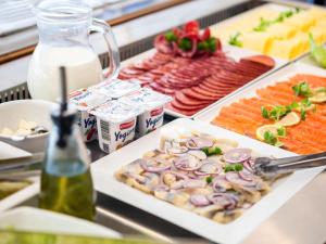 a buffet of food with meats and vegetables and milk at IBIS Styles Kaunas Centre in Kaunas