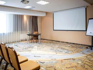 a room with a projection screen and a table and chairs at IBIS Styles Kaunas Centre in Kaunas