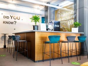 a bar with blue stools in a store at IBIS Styles Kaunas Centre in Kaunas