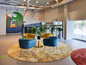 a lobby with chairs and a table in a room at IBIS Styles Kaunas Centre in Kaunas