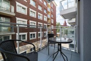 balkon ze stołem i krzesłami oraz budynek w obiekcie Apartments Wrocław Jana Pawła II with FREE PARKING Wrocław by Noclegi Renters we Wrocławiu