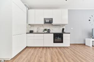 Biała kuchnia z białymi szafkami i drewnianą podłogą w obiekcie Apartments Wrocław Jana Pawła II with FREE PARKING Wrocław by Noclegi Renters we Wrocławiu
