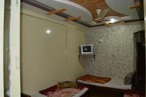 a room with two beds and a tv on the wall at Hotel Deluxe in Kachāhri