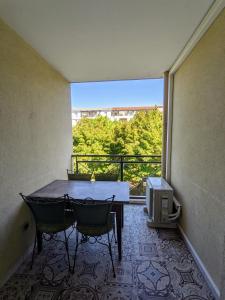balcón con mesa, 2 sillas y ventana en F2 garage box WiFi terasse clim Gare Fac Eco Richter, en Montpellier
