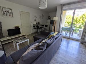sala de estar con sofá azul y cocina en F2 garage box WiFi terasse clim Gare Fac Eco Richter en Montpellier
