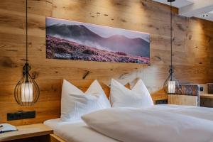 a bedroom with white pillows and a wooden wall at loisi's Boutiquehotel in Achenkirch