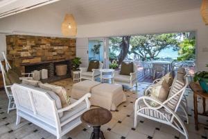 a living room with white chairs and a fireplace at Kwa Thibi Cottage Sleeps 14-with inverter in Umdloti
