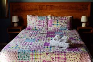 a bed with a quilt and two towels and two lamps at Aconchego De Minas Chalés Visconde de mauá in Resende