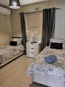 a bedroom with two beds and a dresser and a window at Ann's Place in Umdloti