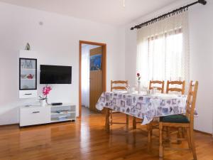 een eetkamer met een tafel en stoelen en een televisie bij Apartment Vera - MLK325 by Interhome in Malinska