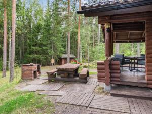 eine Holzterrasse mit einem Tisch und einem Grill in der Unterkunft Holiday Home Salmela by Interhome in Ollila