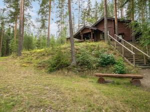eine Blockhütte im Wald mit einer Bank in der Unterkunft Holiday Home Salmela by Interhome in Ollila