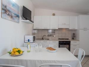 eine weiße Küche mit einem Tisch mit Obst und Weingläsern in der Unterkunft Holiday Home Flamingo by Interhome in Costa Corallina