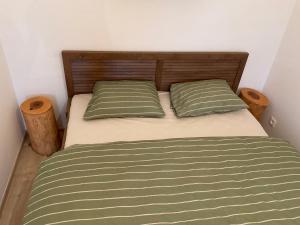 a bed with two green pillows in a bedroom at Útulný jednopokojový apartmán v alpském stylu na Klínovci in Loučná pod Klínovcem