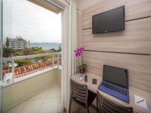Hotel Monteiro Canasvieiras في فلوريانوبوليس: غرفة بها جهاز كمبيوتر على الحائط مع شرفة