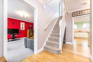 uma escada numa sala de estar com uma parede vermelha em Detached luxury 5 bed house, lanscaped garden, fire pit, parking, can sleep families or workers em Hockering