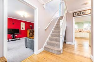 a staircase in a living room with a red wall at Detached luxury 5 bed house, lanscaped garden, fire pit, parking, can sleep families or workers in Hockering