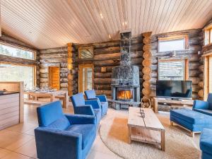 a living room with blue chairs and a fireplace at Holiday Home Jussis chalet b by Interhome in Kuusamo