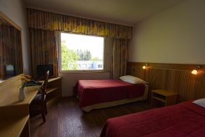 a hotel room with two beds and a window at Hotelli Pesti in Parkano