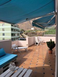 un patio con dosel azul y sillas en el techo en Ático Los Rombos, en Puerto Naos