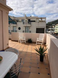 Un balcón con sillas y una mesa y un edificio. en Ático Los Rombos, en Puerto Naos 4 fotos más
