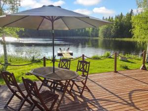 a wooden deck with a table and chairs and an umbrella at Holiday Home Lietukka by Interhome in Outokumpu