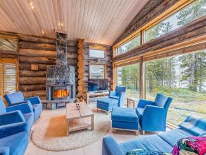 een woonkamer met blauwe stoelen en een open haard bij Holiday Home Jussis chalet a by Interhome in Kuusamo