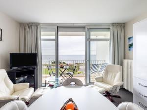 een woonkamer met een tafel en stoelen en een televisie bij Apartment Les Trois Iles-9 by Interhome in Quiberon