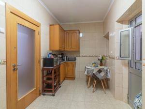 a kitchen with wooden cabinets and a table in it at Holiday Home Felicidade by Interhome in Olhão