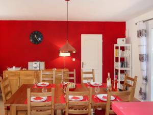 uma sala de jantar com uma mesa e uma parede vermelha em Holiday Home Allegra by Interhome em Le Val