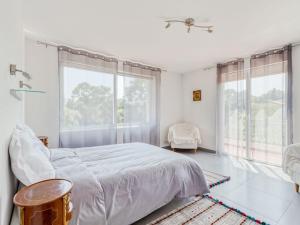 Habitación blanca con cama y ventanas grandes. en Holiday Home Les Nanous by Interhome en Saint-Raphaël