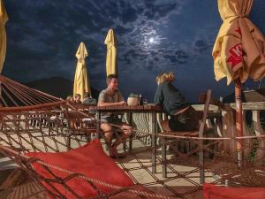 a group of people sitting at a table with umbrellas at Skadar Lake Family Resort in Rijeka Crnojevića